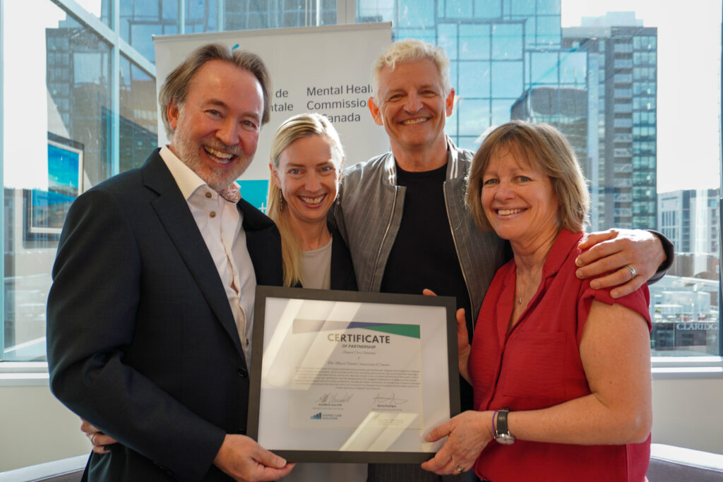 Smiling for a photograph and holding a certificate of partnership between the MHCC and SCS are, left-to-right, Michel Rodrigue, president and CEO at the MHCC, Karla Thorpe, VP of programs and priorities at the MHCC, Fraser Ratchford, strategic advisor at SCS, and AnnMarie Churchill, president and lead executive officer at SCS.