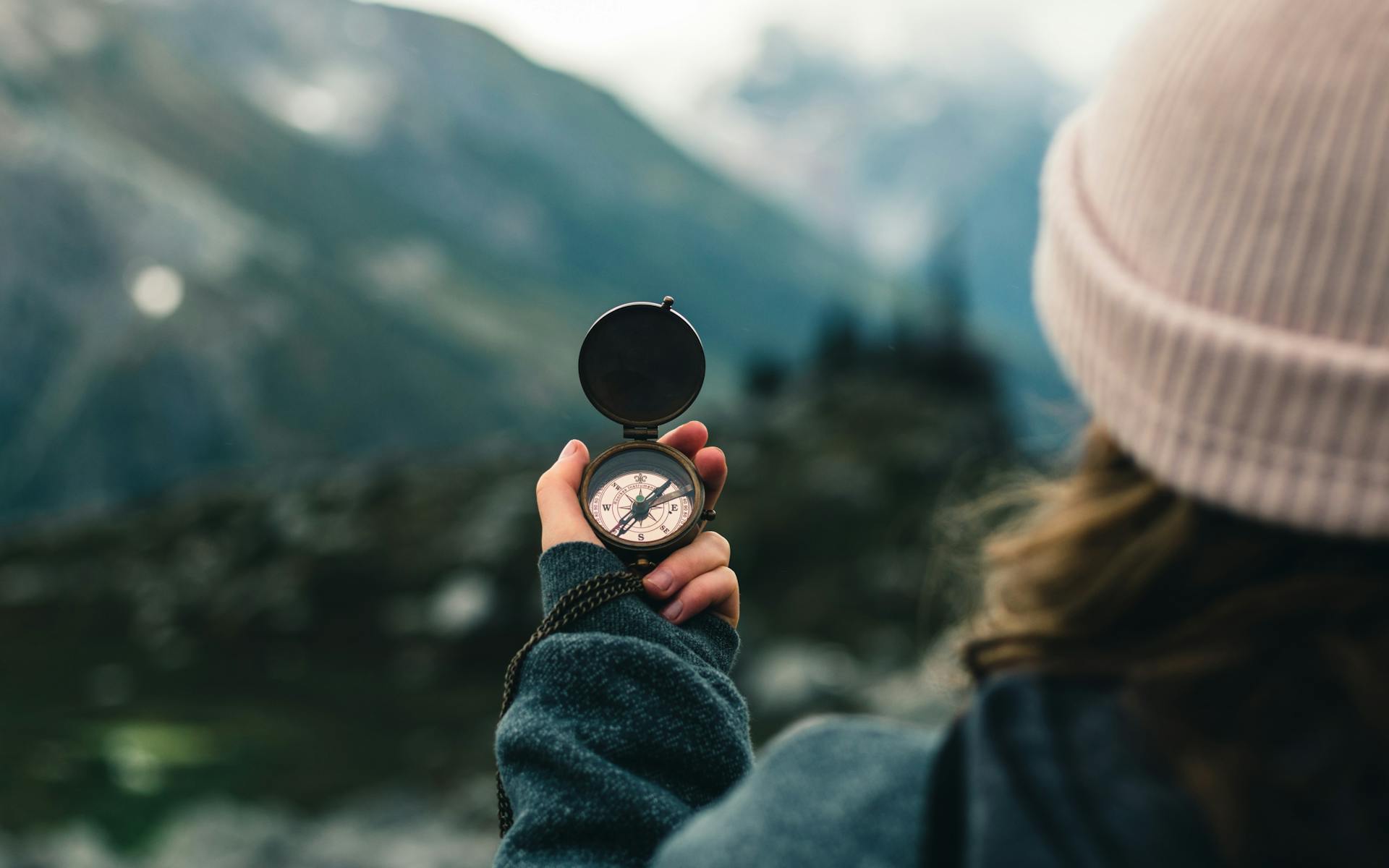 A woman looking out at a mountain range checks a compass for direction